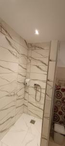 La salle de bains est pourvue de murs en marbre blanc et d'un miroir. dans l'établissement Apartamenty z ogrodem nr 1, à Mrągowo