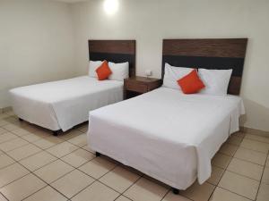 two beds in a room with white and orange pillows at Bed Bed Hotel Abasolo in Torreón