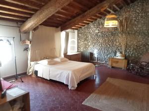 sypialnia z białym łóżkiem i kamienną ścianą w obiekcie Le Mas Palegry Chambres d'hôtes Perpignan w Perpignanie
