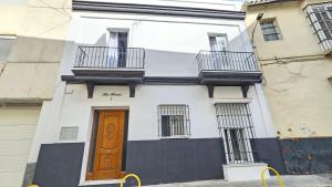 a white building with a brown door and two balconies at Don Roman Suites en pleno centro by Sanlúcar Housing in Sanlúcar de Barrameda