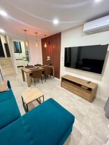 a living room with a blue couch and a large television at Las Americas Bungamar apartment in Playa de las Americas