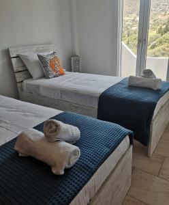 two beds with towels on them in a bedroom at MarGeo View House in Mpatsi, Andros in Batsi