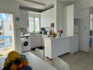 a kitchen with white cabinets and a table with fruit on it at Blue Lagoon Latsi Centre in Lachi