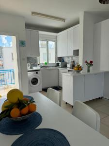 a kitchen with white cabinets and a table with oranges on it at Blue Lagoon Latsi Centre in Lachi