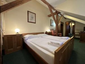 una camera da letto con un grande letto con lenzuola bianche di Hotel U Zámečku Cihelny a Karlovy Vary