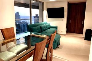 a living room with a green couch and a glass table at Rodadero- Ámbar Deluxe in Santa Marta