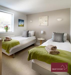 a bedroom with two beds with green blankets at Clearwater - Lower Mill in Somerford Keynes