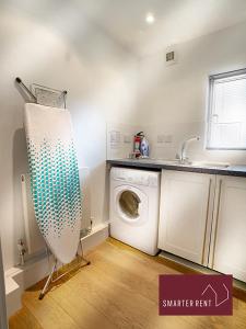 eine Waschküche mit einer Waschmaschine und einem Waschbecken in der Unterkunft Clearwater - Lower Mill in Somerford Keynes