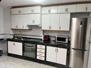 a kitchen with white cabinets and a stainless steel refrigerator at Apartamento Bralo in Padrón
