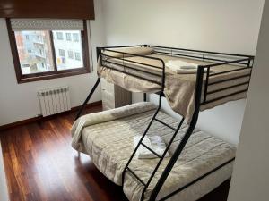 a bunk bed in a room with a bed and a window at Apartamento Bralo in Padrón