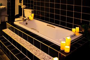 a bath tub in a black tiled bathroom with candles at Black Pearl Apartment New Brighton in Wallasey
