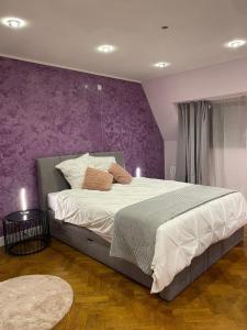 a bedroom with a large bed with a purple wall at Le Joyau de Balmoral in Sart-lez-Spa