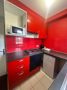 a red kitchen with a stove and a microwave at Sweat Home in Sevran