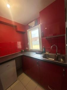 uma cozinha vermelha com um lavatório e uma janela em Sweat Home em Sevran
