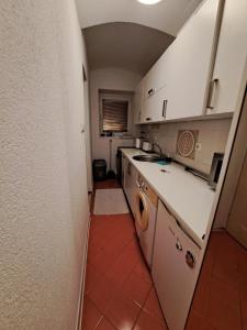 eine kleine Küche mit weißen Schränken und roten Fliesenböden in der Unterkunft Apartment Skenderija Pet friendly with garden in Sarajevo