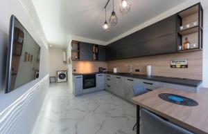 a kitchen with black cabinets and a wooden table at Солнечные просторные апартаменты Метро Минская in Kyiv