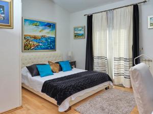 a bedroom with a bed with blue pillows and a window at Art Villa Ines in Zadar