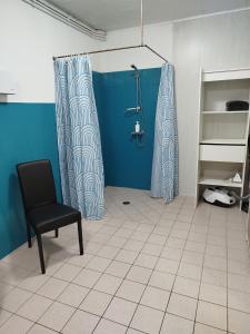 een badkamer met een douche en een zwarte stoel bij Le cheval blanc in Carrouges