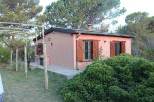 una piccola casa rosa in un cortile con alberi di Los Almendros a Verónica