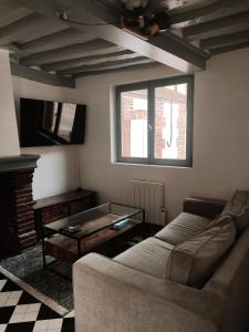 sala de estar con sofá y mesa en Maison en charpentes - 2 nuits minimum, en Lyons-la-Forêt