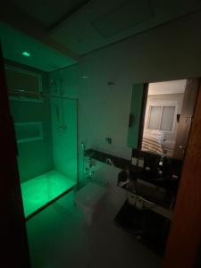 La salle de bains est pourvue d'une pièce verte avec un miroir. dans l'établissement Locação Terras de São Francisco, Quarto Privativo Ipê Amarelo, à Andradas