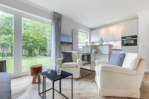 uma sala de estar com mobiliário branco e janelas grandes em Dorfteichblick App 5 em Wenningstedt