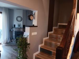 ein Wohnzimmer mit einer Treppe und einer Uhr an der Wand in der Unterkunft Къща за гости В 12 и 5 in Dolna Banya