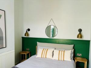 - une chambre avec une tête de lit verte et un miroir dans l'établissement Stylish 3BR house near Liverpool Football Club, à Liverpool