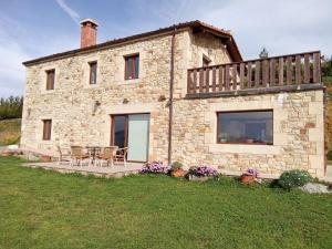 Casa de piedra con mesa y balcón en Casa Rural Costalisa, en Abionzo