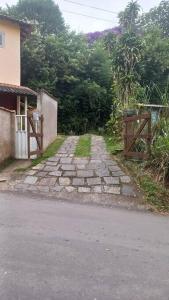 a stone path next to a house with a wooden gate at Chalé urbano in Miguel Pereira
