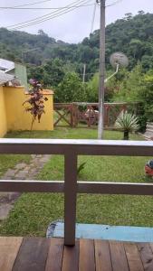 uma varanda com vista para um quintal com uma cerca em Chalé urbano em Miguel Pereira