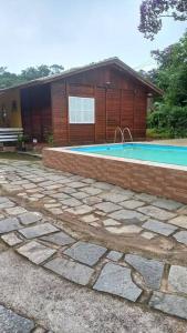 uma casa com piscina em frente a uma casa em Chalé urbano em Miguel Pereira
