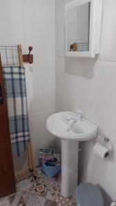 uma casa de banho branca com um lavatório e um espelho em Chalé urbano em Miguel Pereira
