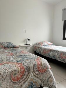 a hotel room with two beds and a table at Complejo Carrodilla - Lujan de Cuyo in Ciudad Lujan de Cuyo