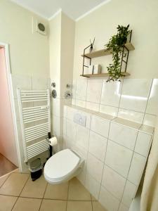 a white bathroom with a toilet and a plant at Traumschmiede in Rellingen