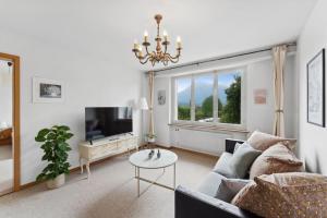 a living room with a couch and a tv and a table at Lakeview apartment in beautiful Oberhofen in Oberhofen am Thunersee