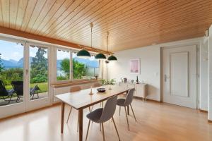 una sala da pranzo con soffitto in legno, tavolo e sedie di Lakeview apartment in beautiful Oberhofen a Oberhofen am Thunersee