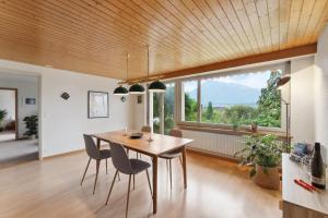 ein Esszimmer mit einem Tisch und Stühlen sowie einem großen Fenster in der Unterkunft Lakeview apartment in beautiful Oberhofen in Oberhofen am Thunersee