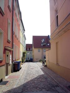 une allée vide dans une ville avec des bâtiments dans l'établissement Apartment BERNSTEIN ruhig, familienfreundlich mit Garten, à Rostock