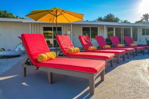 a row of red lounge chairs with an umbrella at Cactus Cove Golf Pool Fitness! in Indio