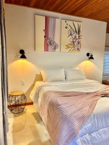 sypialnia z łóżkiem i dwoma obrazami na ścianie w obiekcie Verde da Mantiqueira Chalés w mieście Visconde De Maua