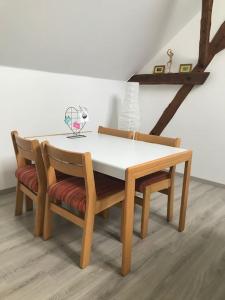 uma mesa de jantar com 2 cadeiras e uma mesa branca em Apartment am See em Weiherhammer