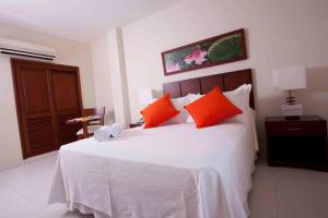 1 dormitorio con 1 cama blanca grande con almohadas de color naranja en Hotel Anaconda, en Leticia