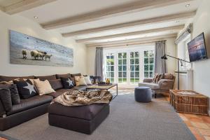 a living room with a brown couch and a tv at Familier Hygge Hus in Braderup