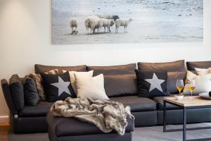 a living room with a brown couch with sheep in the background at Familier Hygge Hus in Braderup