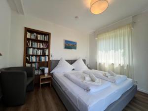 a bedroom with a bed with white sheets and a book shelf at Ferienhaus Wellnesshütte mit Außenwhirlpool und herrlichem See-und Alpenblick in Überlingen