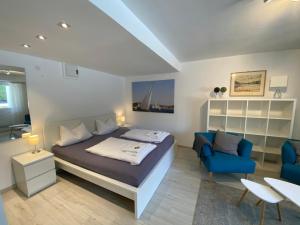 1 dormitorio con 1 cama y 2 sillas azules en Comfort-Appartment, en Überlingen
