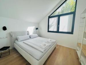 a white bedroom with a bed and a window at seenahe Design-Ferienwohnung Loft Indigo in Überlingen
