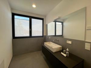 baño con lavabo y espejo grande en seenahe Design-Ferienwohnung Loft Indigo, en Überlingen