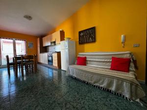 um quarto com uma cama com almofadas vermelhas e uma cozinha em Berchida 1 em La Caletta